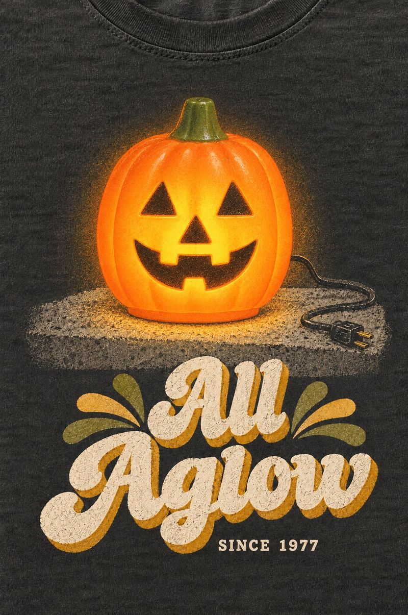 Washed black tee printed with a glowing plastic blow-mold jack-o’-lantern with its cord, words All Aglow, Since 1977