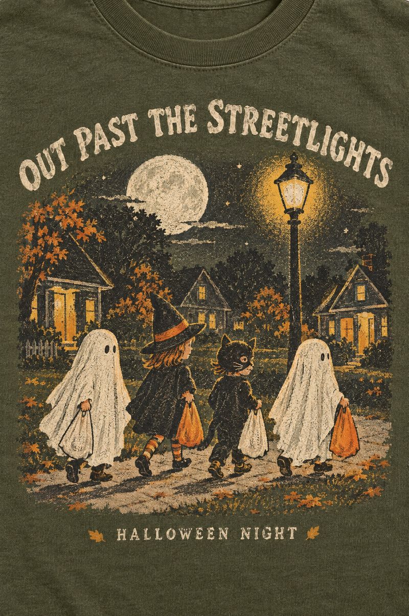 Moss green tee printed with kids in bedsheet ghost, witch and cat costumes carrying pillowcases under a glowing streetlight, words Out Past the Streetlights, Halloween Night